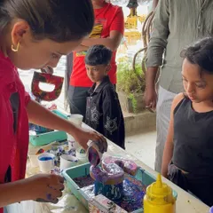 An instructor demonstrates the pouring technique to curious young artists at a birthday party, ensuring everyone feels confident to try it themselves.