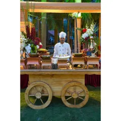 A chef proudly presenting his dish at one of our rustic wooden food carts. We are always ready to serve with a smile.
