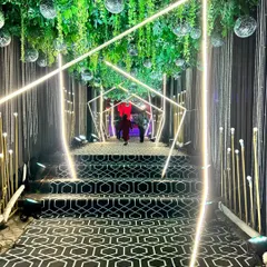 We guide your guests through a mesmerizing geometric tunnel of light for a truly modern and glamorous Sangeet entrance. This immersive walkway, featuring a custom patterned carpet and hanging greenery, sets a sophisticated and high-energy tone for the evening.