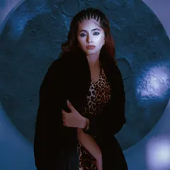 Continuing the cinematic series, this image features the model in a faux fur coat. The cool blue tones and circular backdrop add a mysterious, lunar-inspired aesthetic to the fashion story.