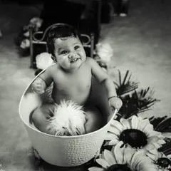 A fun and safe splash time shoot. This black and white photo highlights the joy of our bathtub setup, which includes a classic white tub and surrounding floral props for a touch of whimsy.