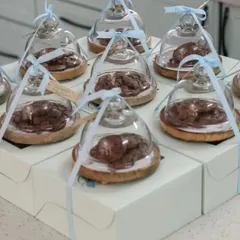 Edible favors are always a hit, especially when presented this beautifully. Here, fresh-baked cookies are placed on a wooden coaster and covered with a glass cloche, then tied with a ribbon.