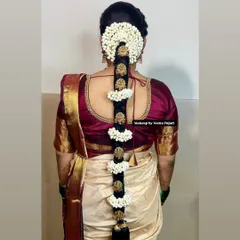 A beautiful Poola Jada hairstyle, featuring sections of fresh jasmine separated by traditional gold hair jewelry. This is a very popular and classic choice for South Indian brides.