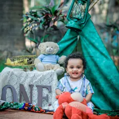Celebrating a first birthday with a camp-themed setup in the park. The little one's happy smile is the centerpiece of this adventurous portrait.