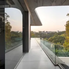 This elevated walkway is wrapped in glass, offering panoramic views of the surrounding greenery. It's a transitional space that allows you to feel connected to the outdoors even while moving through the home.