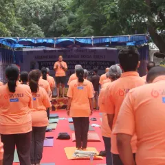 An instructor on stage guiding the large group through poses on International Yoga Day. This highlights the expert instruction provided even in large-scale events.