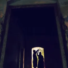 A silhouette of a couple dancing, framed within a dark doorway, creating a sense of intimacy and mystery.