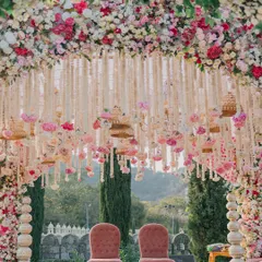 A closer look at a magnificent floral mandap, featuring two regal chairs awaiting the couple. The design incorporates hanging floral strings and birdcages, adding layers of detail and charm to the main ceremony area.