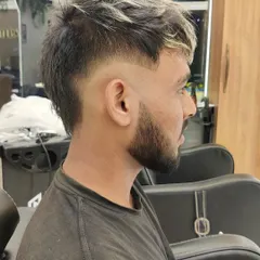 A side view of a men's fade with a textured, highlighted top. This style combines a clean, sharp cut with a touch of creative color for a standout look.