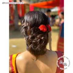 A low messy bun is incredibly versatile. Here, I've added a few simple red flowers to match the client's saree, creating a cohesive and elegant look perfect for an outdoor wedding celebration.