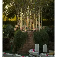 A beautifully decorated tree with hanging floral strings and lanterns, creating a magical seating area for an outdoor wedding function.