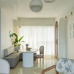 The open layout of this home creates a feeling of spaciousness and light. The dining nook flows seamlessly into the living area, with a cohesive palette of whites, greys, and natural wood tones tying the different zones together.