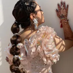 This side view shows how the pearl-accented balloon ponytail adds a fun and fashionable element to the bride's Mehendi look.