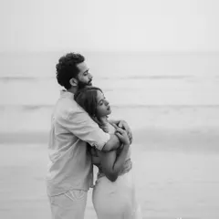 A serene and minimalist black and white photo of Anushka and Himanshu on the beach. The composition emphasizes the feeling of peace and togetherness.