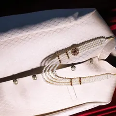 A detail shot of the groom's wedding sherwani and the elegant pearl necklace (mala) that completes his royal look.