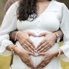 Both parents' hands join to form a heart over the baby bump. This popular pose is a simple yet powerful way to symbolize the love and protection awaiting the new arrival.