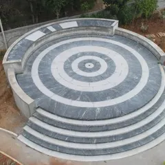 The completed amphitheater at 'The Sanctuary', featuring a striking concentric circle pattern in black and white stone. This space serves as a central focal point and gathering spot for the community.