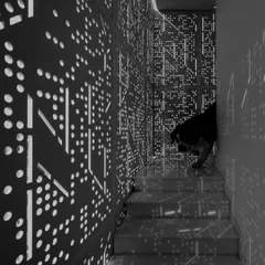 A close-up of the perforated screen at the House Above The Tree, with a furry friend peeking through. The intricate pattern creates a beautiful, diffused light quality, turning a simple stairwell into a magical space.