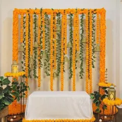 A classic Haldi or Puja ceremony backdrop made entirely of marigold garlands. The hanging bells add a traditional touch to this simple yet beautiful home decoration idea.