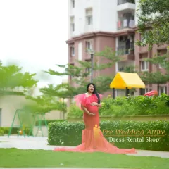 A full-length shot of the red mermaid gown in a park, showing how the train spreads out beautifully on the grass. This dress offers a stunning combination of a figure-hugging fit and a dramatic, flowing base.