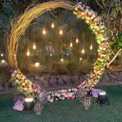 This rustic twig arch, decorated with fresh flowers and hanging Edison bulbs, creates a magical photo point for an evening Mehndi or Haldi function. It's a beautiful blend of natural and modern elements.