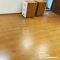 A freshly installed laminate wood floor in a bedroom. Notice the consistent grain and the clean finish against the wall, providing a warm and inviting atmosphere.