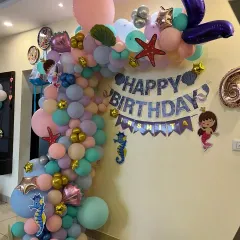A wider view of the mermaid balloon arch, showing its placement in a home setting.