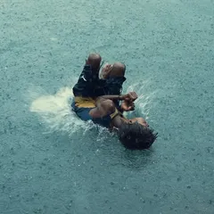 The pure, uninhibited joy of the monsoon. A young boy splashes playfully in a large puddle, a perfect example of the candid, energetic moments that the rainy season brings to the city's streets.