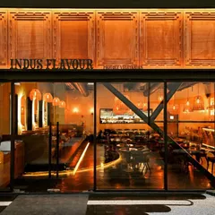 The facade is the first chapter of a brand's story. For the Indus Flavour restaurant, we designed a striking entrance that blends modern architectural lines with traditional motifs, featuring custom wood paneling and warm, inviting exterior lighting that draws patrons in.