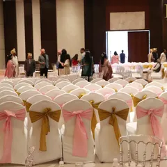 Rows of guest seating with chairs covered in white fabric and adorned with alternating pink and gold bows, adding a touch of color and elegance to the ceremony space.