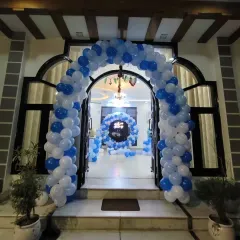 A grand entrance arch in blue and white balloons to welcome a baby boy home. This view shows how an entrance decoration can lead into the main party area inside.