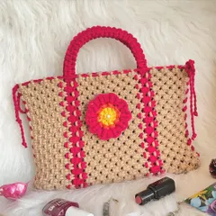 A beautifully handcrafted tote bag in a natural tan color, accented with bright pink stripes and a cheerful flower appliqué. The thick, rounded handles are comfortable to hold.