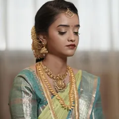 A serene moment from a daylight Muhurtham. The makeup is minimal and elegant, with a focus on a flawless base and soft eye makeup to complement her beautiful silk saree.