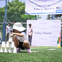 This child is concentrating hard on a cup-stacking challenge during Sports Day. This activity is excellent for developing hand-eye coordination and focus under pressure.