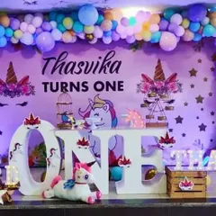 A magical unicorn-themed first birthday for Thasvika. This decoration includes a custom backdrop, large light-up "ONE" letters, a colorful balloon arch, and unicorn props to bring the fantasy to life.