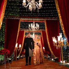 We created a grand, regal entrance for this reception, using rich red drapery, gold accents, and elegant chandeliers. This setup, illuminated by fairy lights and classic candelabras, was designed to make the couple's entrance feel like a royal affair.