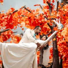 A moment of pure, unscripted laughter during a post-wedding shoot. The vibrant autumn leaves create a stunning backdrop, but it's the couple's genuine joy that makes this photo special.