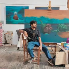 A candid moment in my studio, seated before a large work-in-progress. This space is where my ideas take form, surrounded by finished pieces and the raw materials of my craft.