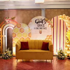 A wider view of the bee-themed naming ceremony decoration. The arrangement of the backdrops, balloon arches, and floral accents creates a full and festive stage for the celebration.