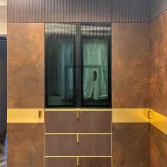 This section of the wardrobe features ribbed glass doors, which offer a glimpse of the clothing inside while maintaining a tidy appearance. Below, the textured drawers and sleek gold handles continue the theme of modern luxury and tactile finishes.