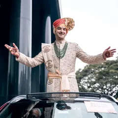The groom making a grand and joyful entrance, standing in his wedding car. This shot captures his excitement and the energy of the baraat.