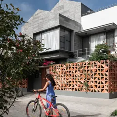 The exterior of 'Roots' showcases a cantilevered volume clad in local stone and a terracotta screen. This combination of textures and forms provides privacy from the street while adding a unique, modern character to the home's facade.