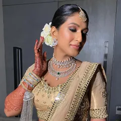 A front-facing view of the elegant bridal look, where the neat bun keeps the focus on the bride's glowing makeup and stunning diamond jewelry.