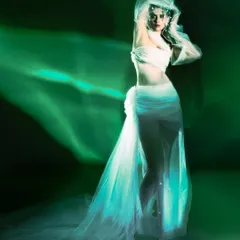 A full-length ethereal portrait from the 'Whispering Veil' series, using green light and motion blur. The model appears as a ghostly figure in a flowing white garment, creating a sense of otherworldly beauty.
