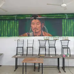 This image shows the tribal man portrait mural in its final setting within a university classroom. The artwork is framed by a painted bamboo motif, connecting the subject to traditional handicrafts and materials.