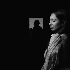 A creative black and white portrait, where the groom's silhouette is reflected in a window as the bride stands in the foreground, creating a layered and thoughtful composition.