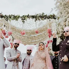 A bride's grand entrance under a delicate phoolon ki chaadar, intricately woven with white flowers and pink accents. This moment captures the blend of tradition and modern elegance that I bring to every wedding.