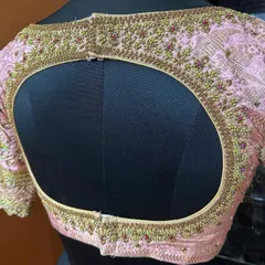 A look at the back of the pink embroidered blouse, featuring a wide keyhole opening framed with detailed beadwork. This design adds a contemporary element to a traditional piece.