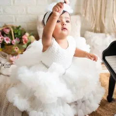 A little angel in a cloud of white tulle. This sitter session captures the sweet curiosity of a baby girl as she reaches for the sky.