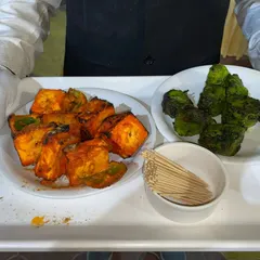 Our professional staff ensures your guests are well taken care of. Here, a server presents freshly made Paneer Tikka and Hariyali Tikka, ready to be enjoyed.